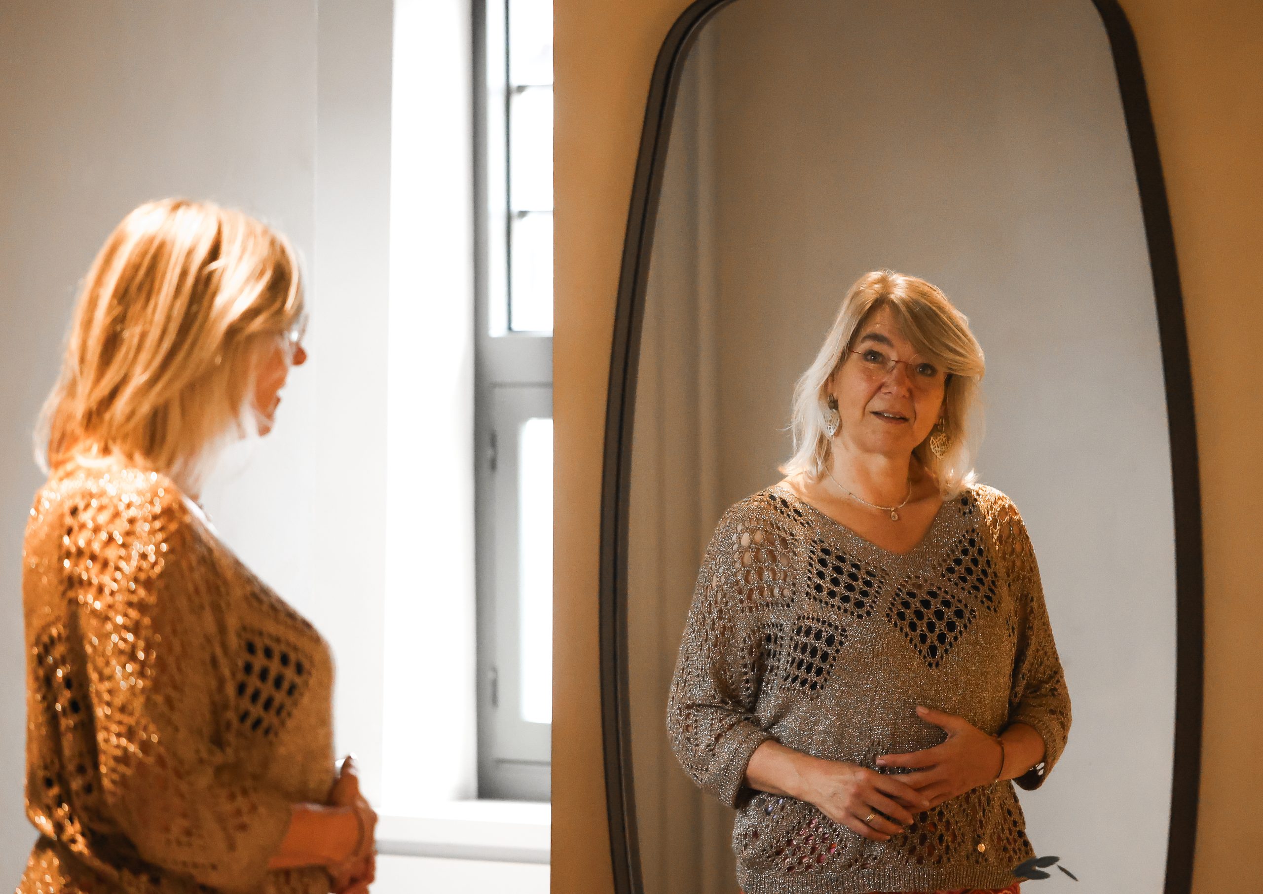 Melanie van De MEL Methode kijkt in de spiegel in een rustige binnenruimte.